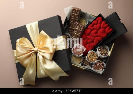 Différents délicieux bonbons au chocolat dans la boîte sur fond beige, vue de dessus Banque D'Images
