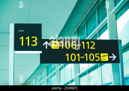 La signalisation lumineuse de l'aéroport affiche les numéros de porte 106 à 112, 101-105, 113. Les flèches directionnelles guident les voyageurs vers leurs zones d'embarquement respectives Banque D'Images