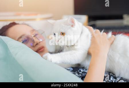 Femme d'âge moyen embrassant chat tabby mignon dans la scène d'intérieur. Les relations homme-animal. Animal domestique avec concept de propriétaire. Banque D'Images