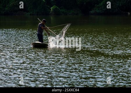 Un pêcheur pêche traditionnellement avec un filet d'un petit bateau sur une rivière. Ninh Binh Ninh Bin Province Vietnam FB 2024 3707 Banque D'Images
