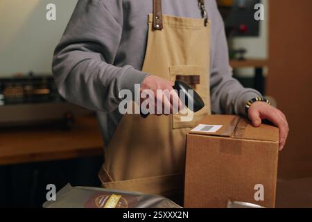 Gros plan moyen d'un ouvrier d'usine méconnaissable scannant le code-barres sur la boîte en carton Banque D'Images