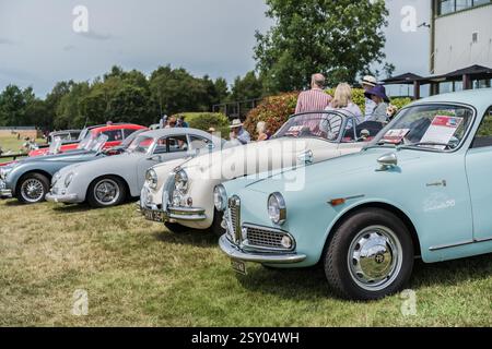 Tarporley, Cheshire, Angleterre, 28 juillet 2024. Une Alfa Romeo Giulia est exposée lors d'une rencontre de voitures anciennes, avec des gens qui socialisent en arrière-plan. Banque D'Images