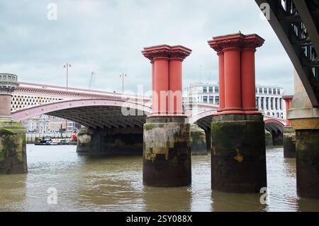 Vue sur les piliers du pont ferroviaire Old Blackfriars en face de Blackfriars Road et du pont piétonnier traversant la Tamise, Londres Royaume-Uni Banque D'Images