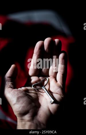 Une main tenant une clé. sur fond rouge Banque D'Images