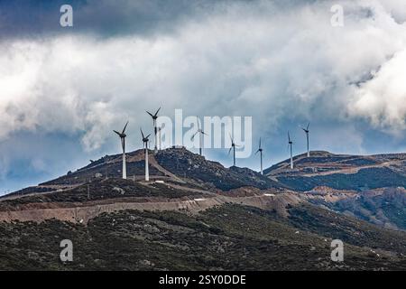 Une vue panoramique des éoliennes positionnées au sommet d'une crête de montagne accidentée sous un ciel sombre et nuageux, représentant l'énergie renouvelable et la beauté naturelle. Banque D'Images