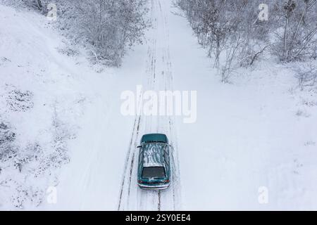 Vue aérienne d'une voiture circulant sur route glacée en forêt Banque D'Images