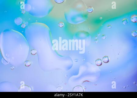 Fond abstrait coloré avec des bulles d'huile flottant dans l'eau. Les nuances dégradées de bleu, rose, jaune et vert créent un effet doux et aéré. Colore Banque D'Images