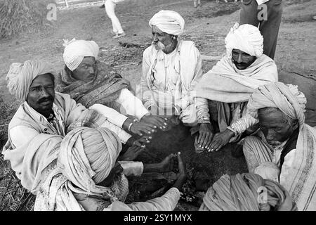Sept hommes réchauffant les mains en hiver froid Vautha Fair Gujarat Inde Asie 1983 Banque D'Images