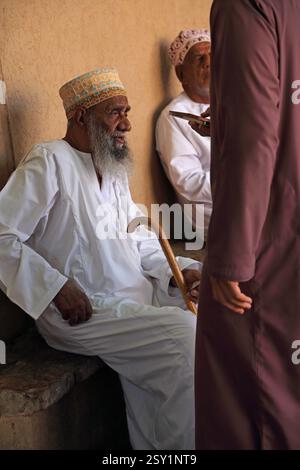 Homme omanais âgé avec bâton de marche assis au marché de Nizwa Oman Banque D'Images