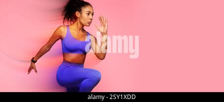 Sportive jeune femme afro-américaine qui court avec une expression confiante, fond rose Banque D'Images