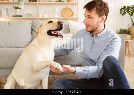 Jeune homme jouant avec le chien à la maison Banque D'Images