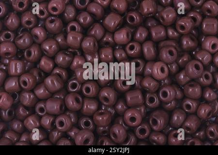 Perles marron sur le fond blanc. Fond ou texture de perles. Gros plan, macro, il est utilisé dans la finition des vêtements de mode. faire collier de perles ou s Banque D'Images