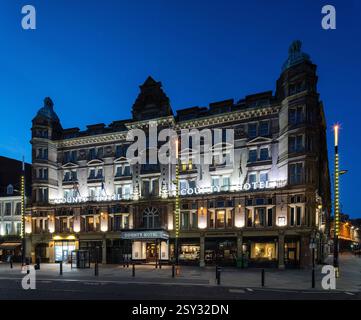 Une vue extérieure au crépuscule du County Hotel à Newcastle upon Tyne vue de la gare centrale de Newcastle avec éclairage par projecteurs et les chambres éclairées Banque D'Images