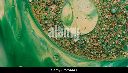 Blob acrylique. Mélange de peinture. Goutte de gel de particules métalliques chatoyantes flottant dans l'eau verte. Arrière-plan abstrait de bulle d'humidité défocalisée. Banque D'Images