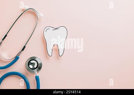 Dent coupée en papier avec stéthoscope sur rose pastel pour la Journée des dentistes. Mettre en évidence la santé dentaire, l'orthodontie et les soins bucco-dentaires à travers une maquette créative desig Banque D'Images