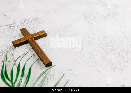 Thème du dimanche des palmiers : croix en bois et frondes de palmier sur fond naturel. Reflétant la célébration de Pâques, la foi et la signification religieuse dans une symbolique Banque D'Images