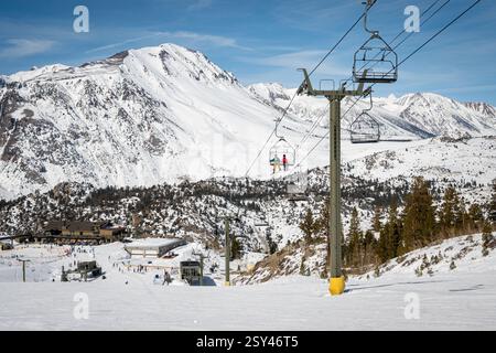 Un skieur et un snowboarder montent sur un télésiège à la station de June Mountain, nichée dans les montagnes de Pâques de la Sierra Nevada. Banque D'Images