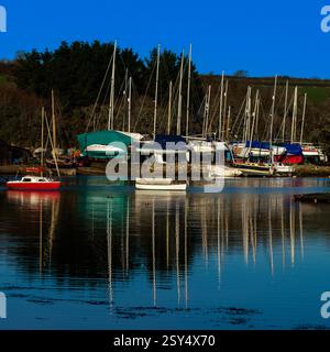 En décembre, le soleil, une légère brise ondule doucement la surface de la St Just Creek à St Just à Roseland, Cornwall, Angleterre, Royaume-Uni, car elle reflète les mâts de yachts posés pour l'hiver dans un chantier naval. Le ruisseau de marée de la péninsule de Roseland, est une entrée de l'estuaire de la rivière FAL, menant à Carrick Roads et à la mer ouverte. Banque D'Images