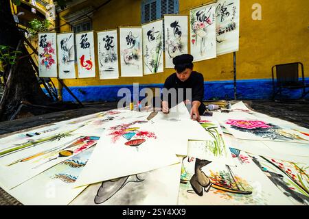 Un artiste peint des tableaux colorés avec des caractères chinois anciens sur un sentier à Hoi an, Hái an. Province de Hoi an Quang Nam Vietnam FB 2024 4230 Banque D'Images