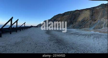 Vue panoramique sur le paysage belle plage de sable avec ciel bleu structure de barrière de défense en bois piscines L'eau de mer reflètent le ciel et les falaises de craie Norfolk Royaume-Uni Banque D'Images