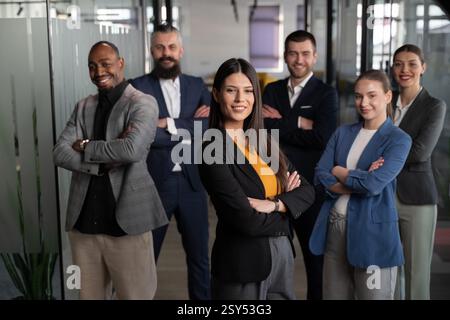 Femme d'affaires confiante debout, les bras croisés, dirigeant une équipe diversifiée dans un bureau moderne. Concept de leadership, travail d'équipe, succès d'entreprise Banque D'Images