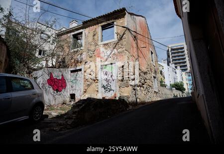 Bâtiment abandonné avec des murs en ruine et des graffitis sur une rue étroite en montée à Lisbonne Banque D'Images