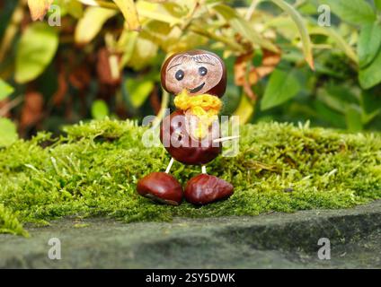 figurine drôle de châtaigne avec écharpe jaune sur mousse Banque D'Images