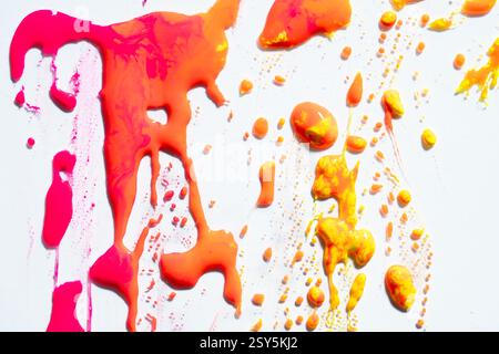 Gouttes de peinture humide orange vibrant abstrait et splotch sur fond blanc. Couleurs néon vives. Street art isolé Banque D'Images