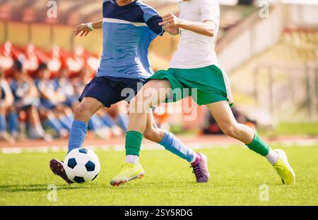 Joueur de football frappant un ballon sur le terrain. Duel de football entre deux joueurs. Des joueurs de football adultes s'affrontent dans une course. Compétition sportive sur le stade Banque D'Images