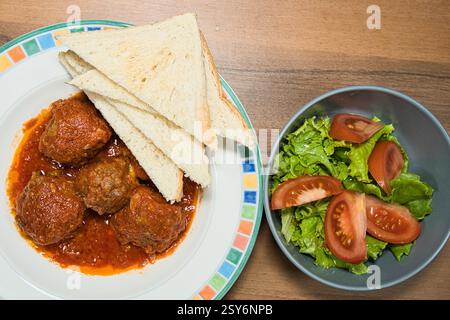 Boulette de viande avec garnitures de fromage en sauce, avec tranche de pain blanc et salade de tomates et de laitue Banque D'Images