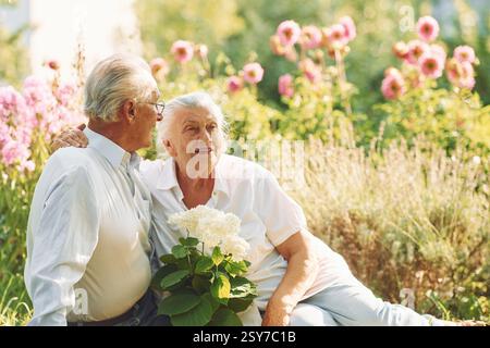 Assis sur le sol. Charmant couple aîné est dans le jardin ensemble. Banque D'Images