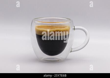 Un double espresso, isolé dans une tasse à café transparente. Banque D'Images