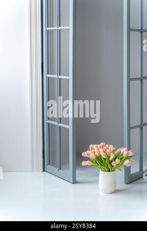 Intérieur minimaliste : canapé blanc, murs blancs, regardez le canapé et le vase avec des tulipes inférieures Banque D'Images