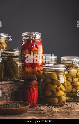 Des pots de légumes marinés, sont disposés sur une table en bois rustique, mettant en valeur des techniques de conservation maison Banque D'Images