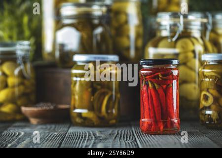Des pots de piments rouges marinés et divers légumes, créant un affichage coloré et savoureux des aliments conservés Banque D'Images
