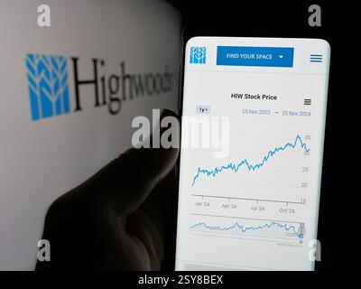 Dans cette illustration photo, une personne tient un téléphone portable avec la page Web de la société immobilière américaine Highwoods Properties Inc sur l'écran avec logo. Banque D'Images