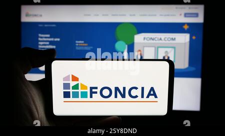 Allemagne. 26 novembre 2024. Dans cette illustration photo, une personne tient un téléphone portable avec le logo de la société immobilière française Foncia SAS sur l'écran devant la page Web de l'entreprise. (Crédit image : © timon Schneider/SOPA images via ZUMA Press Wire) USAGE ÉDITORIAL SEULEMENT ! Non destiné à UN USAGE commercial ! Banque D'Images