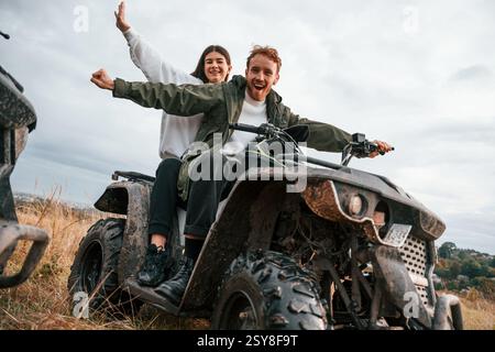 S'amuser en étant assis. Beau jeune couple est avec quad à l'extérieur sur le terrain. Banque D'Images