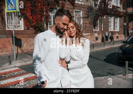 Debout et embrassant les uns les autres. Beau jeune couple est ensemble dans la rue contre le vieux bâtiment. Banque D'Images