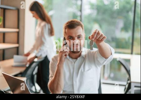 Tenant les clés pour le nouvel appartement. Homme et femme travaillent ensemble dans le bureau moderne. Banque D'Images