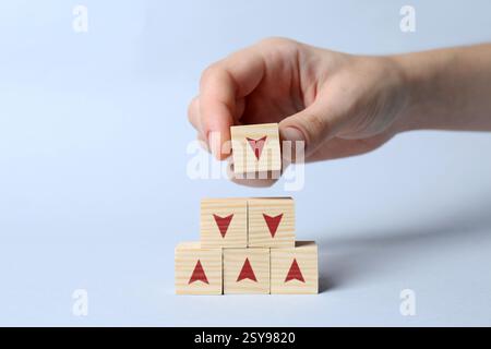 Femme empilant des cubes en bois avec des flèches sur fond blanc, gros plan Banque D'Images