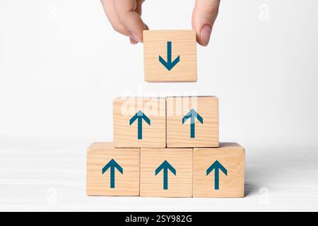 Femme empilant des cubes en bois avec des flèches bleues sur fond blanc, gros plan Banque D'Images