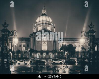 Une photographie en noir et blanc capture l'hôtel de ville de San Francisco la nuit, illuminée par des lampadaires et des projecteurs. Banque D'Images
