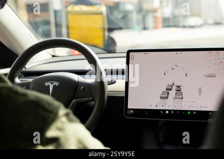 Porto, Portugal - 07.2024 : tableau de bord voiture électrique TESLA Model 3. Tableau de bord intérieur avec design d'interface moderne et décoration de volant. Banque D'Images