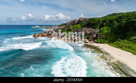 Rochers de granit entourés de verdure luxuriante et de vagues turquoises le long de la côte. La Digue, Seychelles. Banque D'Images