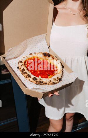 Gros plan d'une pizza au pepperoni au Chili cuite au feu de bois garnie de salami, de mozzarella, de sauce tomate et de piments. Servi dans une boîte à emporter, prêt à être Banque D'Images