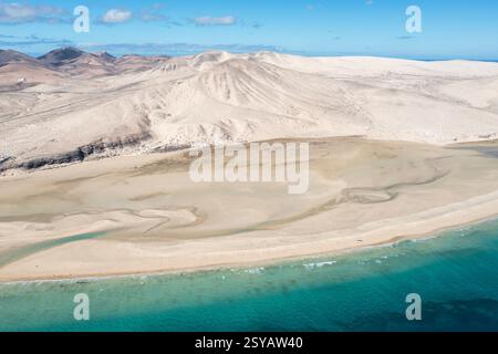 La prise de vue aérienne capture le vaste paysage sablonneux et les eaux Azur de la plage de Sotavento, Fuerteventura, mettant en évidence les motifs uniques de la plage Banque D'Images