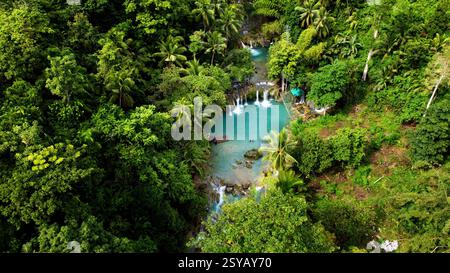 Une photo aérienne montrant la verdure luxuriante et les eaux turquoises vibrantes d'une cascade tropicale isolée aux Philippines, idéale pour les vacances et Banque D'Images