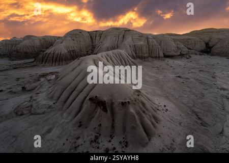 Un coucher de soleil spectaculaire illumine les formations rocheuses en couches de Bisti/de-Na-Zin Wilderness au Nouveau-Mexique, projetant une lueur chaude sur le paysage unique. Banque D'Images