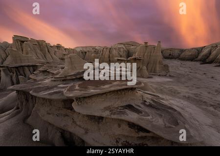 Un coucher de soleil spectaculaire illumine les formations rocheuses uniques de la nature sauvage de Bisti/de-Na-Zin au Nouveau-Mexique, projetant des couleurs surréalistes sur les sables sculptés Banque D'Images